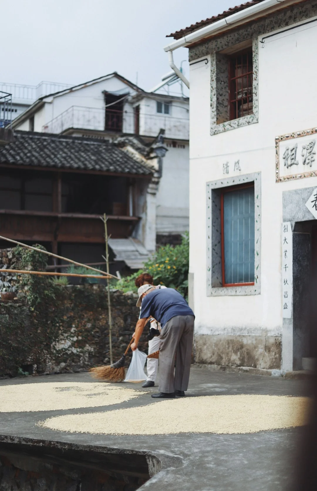 A man in a blue t-shirt cleaning large glass pane with a squeegee indoors.